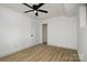A bedroom featuring light wood flooring, white walls, black door hardware and a ceiling fan at 7407 Forney Hill Rd, Denver, NC 28037