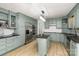 Stylish kitchen with pastel green cabinets, stainless steel appliances, an island, and modern lighting at 7407 Forney Hill Rd, Denver, NC 28037