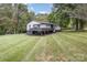 Back of house featuring a big yard, white siding, black brick base, and a carport at 7407 Forney Hill Rd, Denver, NC 28037