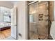 Tiled glass shower with built-in shelves for storage and a door open to a bedroom with hardwood floors and neutral decor at 7613 Whistlestop Rd, Charlotte, NC 28210
