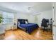 Bedroom featuring hardwood floors, white walls, and a blue comforter on the bed, with desk area and natural light at 7613 Whistlestop Rd, Charlotte, NC 28210