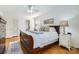 Bright bedroom with hardwood floors, two windows, and a dark wood bed frame with a plush white comforter and pillows at 7613 Whistlestop Rd, Charlotte, NC 28210