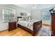 Cozy bedroom featuring hardwood floors, two windows for natural light, and a dark wood bed frame with decorative pillows at 7613 Whistlestop Rd, Charlotte, NC 28210