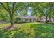 Well-maintained white house with a green lawn and mature trees on a sunny day at 7613 Whistlestop Rd, Charlotte, NC 28210