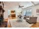 Bright living room with hardwood floors, ceiling fan, and comfortable seating near the fireplace and open to the kitchen at 7613 Whistlestop Rd, Charlotte, NC 28210