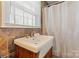Bathroom featuring a vanity sink, stone walls, a window, and a white shower curtain at 8101 Kerrybrook Cir, Charlotte, NC 28214