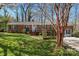 Charming single-story brick home with a lush green lawn and trees, featuring a cozy front porch at 8101 Kerrybrook Cir, Charlotte, NC 28214