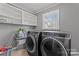 Functional laundry room featuring a modern washer and dryer, storage shelves, and a bright window at 8101 Kerrybrook Cir, Charlotte, NC 28214