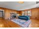 Comfortable living room featuring wood paneling, a brick fireplace, and a large blue sofa on an area rug at 8101 Kerrybrook Cir, Charlotte, NC 28214