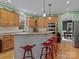 Bright kitchen features wooden cabinetry, granite countertops, stainless steel appliances, red barstools and hardwood floors at 9904 Duane Ct, Huntersville, NC 28078