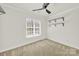 Bright, carpeted bedroom with a ceiling fan, a large window, and black shelving at 11000 King George Ln, Waxhaw, NC 28173
