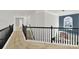 Well-lit hallway with neutral carpet, black railing, and a view of the staircase at 11000 King George Ln, Waxhaw, NC 28173