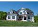 Beautifully landscaped two-story home with a covered front porch, American flag, and lush green lawn at 129 Ryleigh Dan Pl, Mooresville, NC 28115