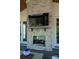 Close-up of outdoor fireplace with stone surround and mounted TV on the screened porch at 129 Ryleigh Dan Pl, Mooresville, NC 28115
