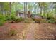 Backyard brick pathway leading to a grey home with a brick chimney amidst lush foliage and azaleas at 140 Rustic Way Ln, Mooresville, NC 28117
