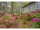 Landscaped backyard with azaleas lining a brick path to a gray house with lush trees and a wooded backdrop at 140 Rustic Way Ln, Mooresville, NC 28117