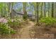Secluded home exterior with brick accents, surrounded by mature trees and vibrant azaleas, offering a tranquil setting at 140 Rustic Way Ln, Mooresville, NC 28117