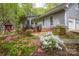 Charming home exterior with gray siding, brick foundation, and colorful flowering shrubbery at 140 Rustic Way Ln, Mooresville, NC 28117