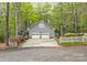 Detached two-car garage with white doors and siding, accented by a white fence and spring blooms at 140 Rustic Way Ln, Mooresville, NC 28117