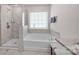 Bright bathroom with white tub, glass shower, and marble tiling at 155 Autumnwood Rd, Troutman, NC 28166