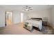Comfortable bedroom with neutral decor, ceiling fan, carpet and upholstered storage bench and two doorways at 3899 Center Place Dr, Harrisburg, NC 28075
