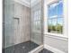 Modern walk-in shower featuring glass doors, grey tiled walls, and black honeycomb-patterned floors at 4008 Nettie Ct # 3, Charlotte, NC 28211