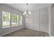 Dining room with elegant chandelier, wainscoting detail, wood floors and abundant natural light from large windows at 531 Harlech Ct, Fort Mill, SC 29715