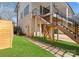 Back yard featuring a staircase to the upper balcony, a stone paver path, and manicured grass at 5520 Chedworth Dr, Charlotte, NC 28210