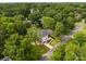 Aerial view of the modern home surrounded by lush green trees in a quiet neighborhood at 5610 Farmbrook Dr, Charlotte, NC 28210