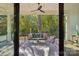 A covered balcony has a seating area with a ceiling fan overlooking a wooded area at 5610 Farmbrook Dr, Charlotte, NC 28210