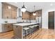 Bright kitchen features a large island with seating, pendant lighting, stainless steel appliances, and wooden floors at 5610 Farmbrook Dr, Charlotte, NC 28210