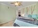 Cozy bedroom with a decorative tree mural, ceiling fan, and comfortable bed with blue and gray accents at 6523 Matlea Ct, Charlotte, NC 28215