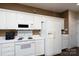 Kitchen features white appliances, white cabinetry, and dark wood-look flooring, with contrasting brown-painted walls above at 8568 Windsor Ridge Dr, Charlotte, NC 28277