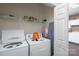 Laundry room featuring a white washer and dryer set, storage shelf, and ironing board at 8568 Windsor Ridge Dr, Charlotte, NC 28277