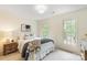 Neutral bedroom with a queen bed, side table, and windows with views of mature trees at 1006 Baldwin Ln, Waxhaw, NC 28173