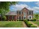 Traditional brick home with manicured lawn, black shutters, and lush landscaping creating a welcoming curb appeal at 1006 Baldwin Ln, Waxhaw, NC 28173