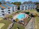 Aerial view of a community swimming pool area with well maintained landscaping, condos, and a lake at 1008 Southwest Dr # 8, Davidson, NC 28036