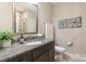 Bathroom featuring granite countertop, dark cabinetry, framed mirror and a tiled shower at 15103 Honeycutt Dr, Huntersville, NC 28078