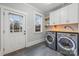 Bright laundry room features slate tile flooring, washer and dryer, and built in cabinets with wood countertop at 331 Solomon St, Charlotte, NC 28216