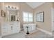 A bright bathroom with tub, white cabinets, modern fixtures, and picture window at 409 Running Horse Ln, Waxhaw, NC 28173