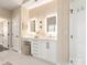 Elegant bathroom features dual sinks with marble countertops, white cabinetry, and backlit mirrors at 409 Running Horse Ln, Waxhaw, NC 28173