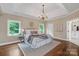 Elegant bedroom with hardwood floors, chandelier, tray ceiling, and bright windows at 409 Running Horse Ln, Waxhaw, NC 28173