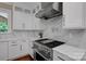 A bright kitchen features white cabinets, marble backsplash, stainless steel hood, and Wolf gas range at 409 Running Horse Ln, Waxhaw, NC 28173