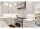 Close up view of a gourmet kitchen with stainless steel stove, marble backsplash, and sleek white cabinets at 409 Running Horse Ln, Waxhaw, NC 28173
