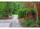 Landscaped yard with a stone pathway, lush greenery, and a variety of plants and flowers at 409 Running Horse Ln, Waxhaw, NC 28173