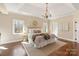 Spacious main bedroom with a tray ceiling, hardwood floors, a chandelier, and plenty of natural light from multiple windows at 409 Running Horse Ln, Waxhaw, NC 28173