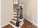 Interior staircase featuring hardwood steps, a decorative wood banister, and neutral paint colors at 409 Running Horse Ln, Waxhaw, NC 28173
