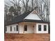 Charming white home with black roof, siding, and dark framed windows, surrounded by bare trees at 635 Academy St, Cleveland, NC 27013