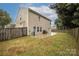 Wide backyard showcasing a well-kept lawn, bordered by a wooden fence, with a patio and mature trees at 128 Lacona Trce, Mooresville, NC 28115