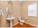Features a pedestal sink, round mirror, and wood-look flooring with neutral wall color at 128 Lacona Trce, Mooresville, NC 28115